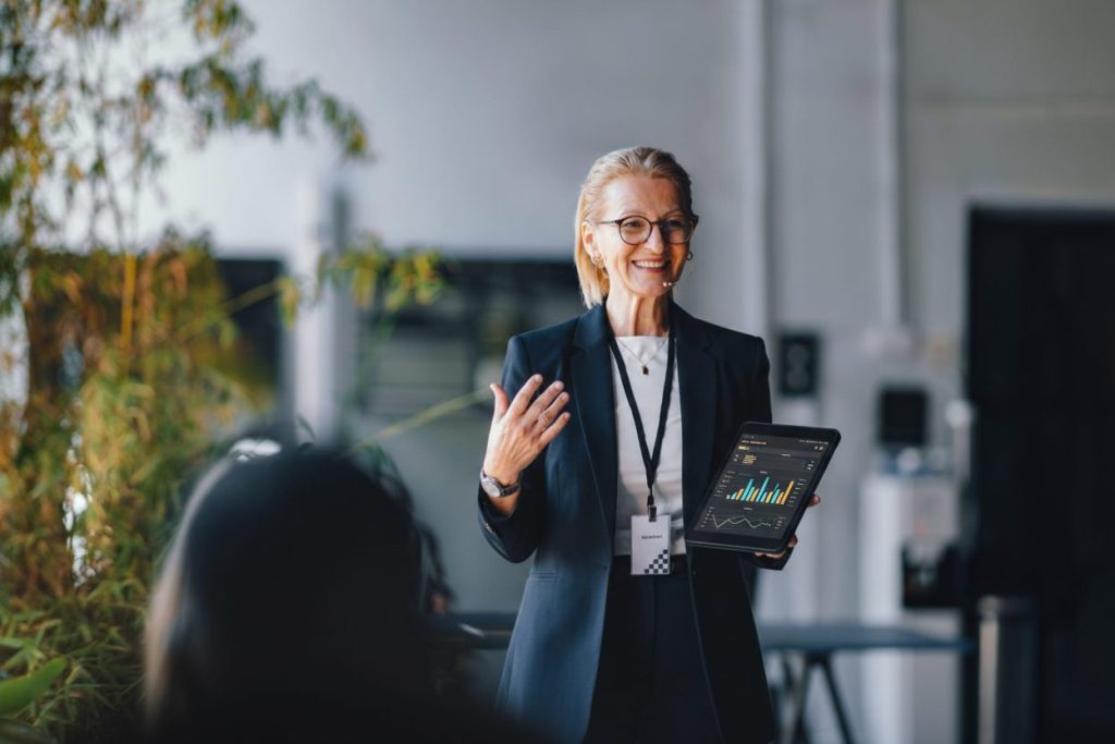 Professional business leader presenting data insights on a tablet during a corporate meeting, demonstrating thought leadership and strategic decision-making
