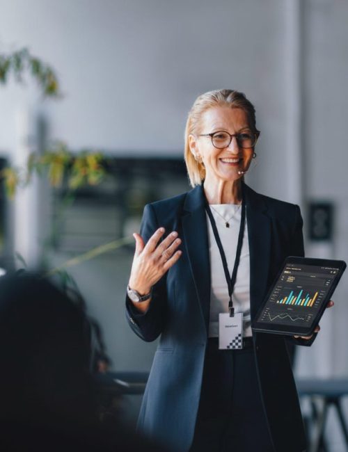 Professional business leader presenting data insights on a tablet during a corporate meeting, demonstrating thought leadership and strategic decision-making