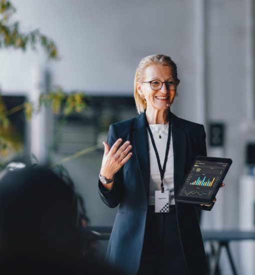 Professional business leader presenting data insights on a tablet during a corporate meeting, demonstrating thought leadership and strategic decision-making
